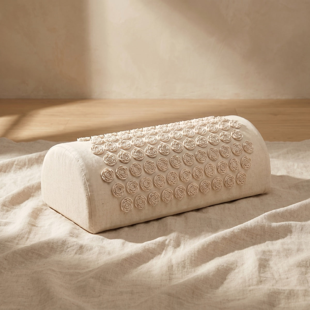Restora mini acupressure bolster pillow on linen — serene still life